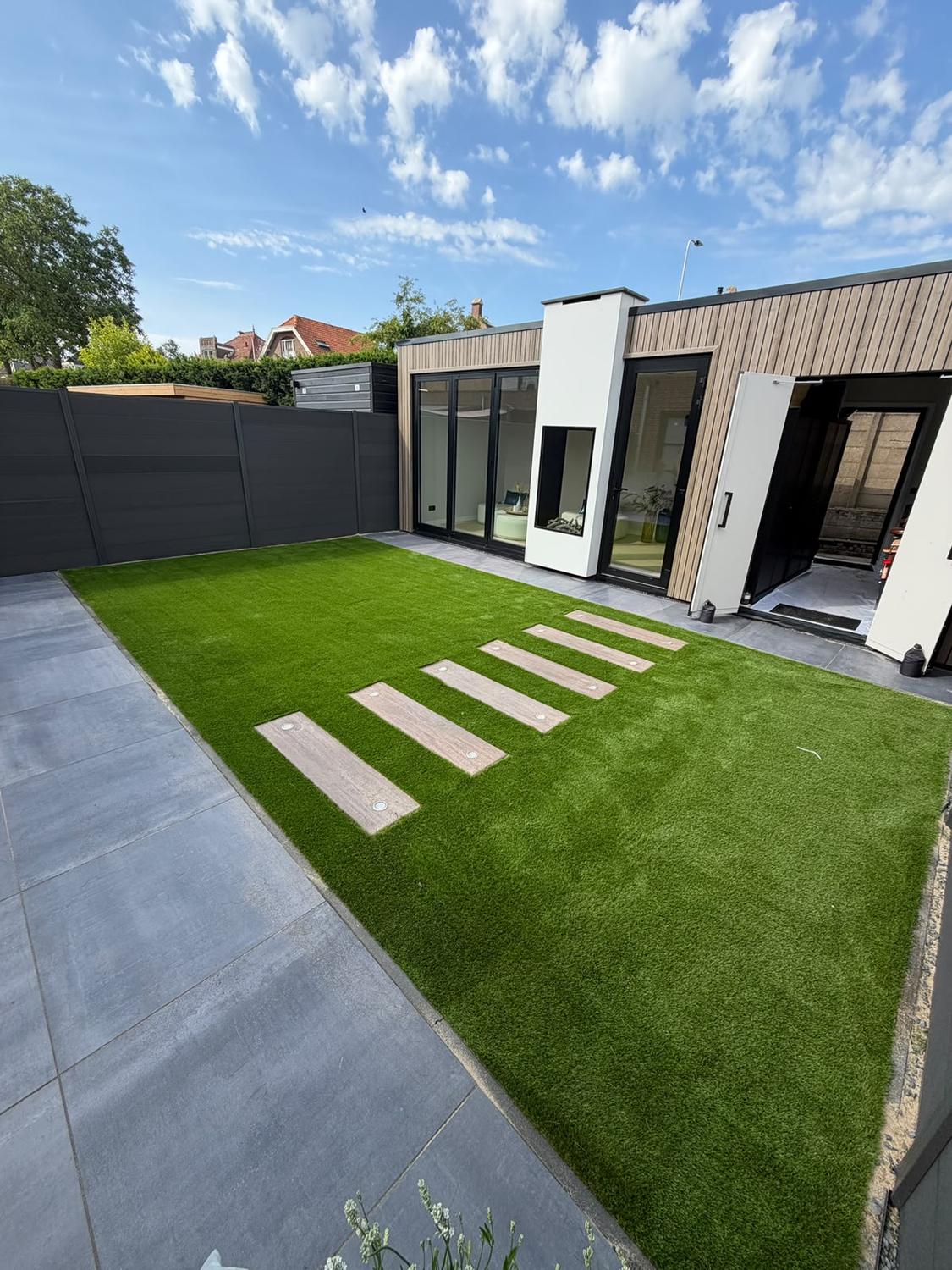 Moderne tuin met kunstgras dat strak aansluit op een ruim terras