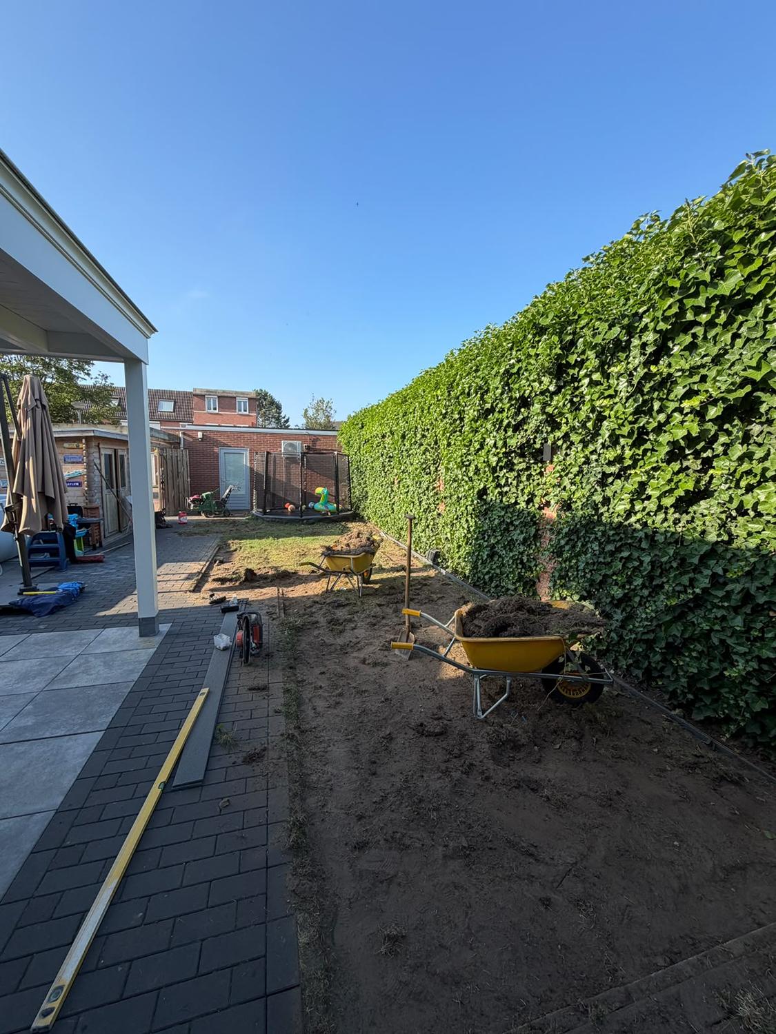 Tuin tijdens de aanleg, met uitgevlakte en verdichte fundering klaar voor kunstgras